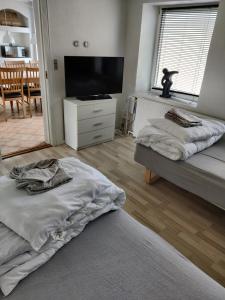 a bedroom with two beds and a flat screen tv at 210 m2 hus med plads til 8 gæster in Nordborg