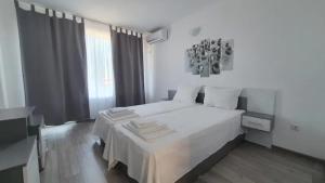 a white bedroom with a white bed and a window at Къща за гости - Пролет in Lozenets