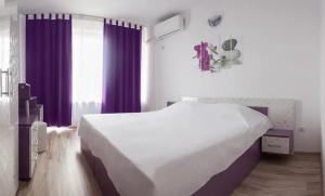 a bedroom with a large white bed and purple curtains at Къща за гости - Пролет in Lozenets