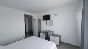 a white bedroom with a bed and a flat screen tv at Къща за гости - Пролет in Lozenets
