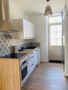 una cucina con armadi bianchi e piano di lavoro di Centre ville (1) : superbe appartement climatisé a La Flèche