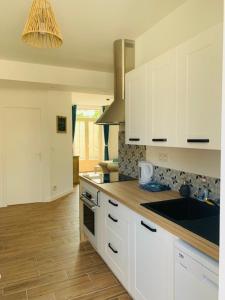 a kitchen with white cabinets and a wooden floor at Centre ville (1) : superbe appartement climatisé in La Flèche