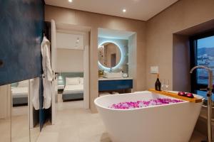 un baño con una gran bañera con flores rosas. en Artis Blue Relax en Himare