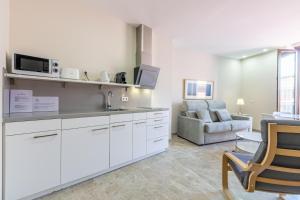 a kitchen with white cabinets and a living room with a couch at Green-Apartments Alto de Santa Cruz in Seville