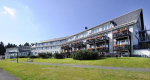 Un grand bâtiment blanc avec des fleurs sur les balcons dans l'établissement Ferienhaus Nr 1 Sporthotel Oberhof, à Oberhof