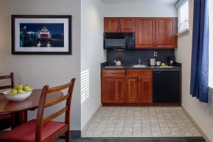 a kitchen with wooden cabinets and a table with a bowl of fruit at Federal City Inn & Suites in New Orleans +17 photos