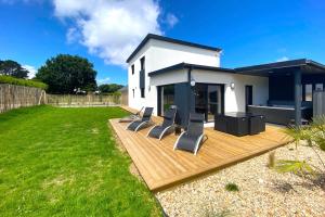a backyard with a deck with chairs and a house at carantec 4 stars villa with jacuzzi and garden for 8 persons in Carantec