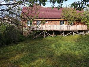 a brick house with a wooden deck in a yard at Borlova /Muntele Mic in Borlova