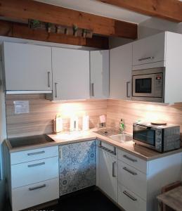 a kitchen with white cabinets and a microwave at MeerMomente in Dorum-Neufeld