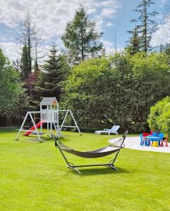 a playground with a hammock in a yard at Willa Liliowa in Dębki
