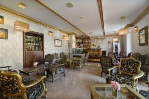 une salle d'attente avec des chaises, des tables et un bar dans l'établissement Hotel Aurum, à Hajdúszoboszló