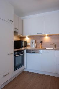 uma cozinha com armários brancos e um forno com placa de fogão em Gästehaus Alpenstern em Ehrwald