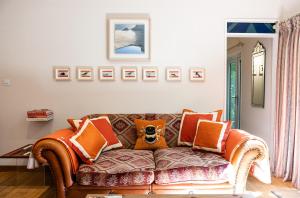 a living room with a brown couch with orange pillows at THE HYDE- secret hide away, near the beach. in Truro