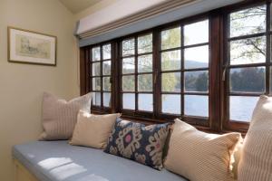 Sofá azul con almohadas en una habitación con ventanas en The Queen's Hut, en Aboyne