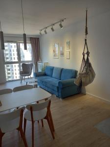 Przytulny Apartament nad morzem في غدانسك: غرفة معيشة مع أريكة زرقاء وطاولة