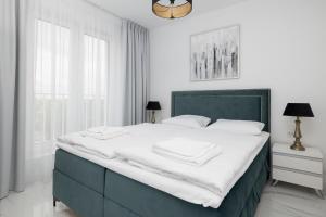 sypialnia z dużym łóżkiem z białymi prześcieradłami w obiekcie Apartament DIAMOND w Kołobrzegu