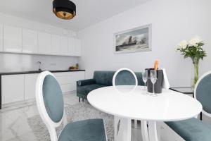 biała jadalnia z białym stołem i krzesłami w obiekcie Apartament DIAMOND w Kołobrzegu