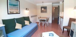 ein Wohnzimmer mit einem blauen Sofa und einer Küche in der Unterkunft Appartement Lacanau entre Golf et Océan pour 4 personnes in Lacanau
