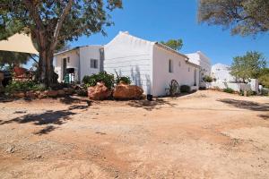 een wit huis met een boom en een onverharde weg bij Casa Cobra in Moncarapacho