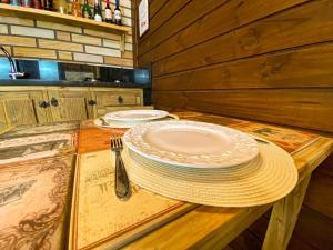 a wooden table with two plates and a fork and knife at Chalé Miragem dos Canyons in Praia Grande
