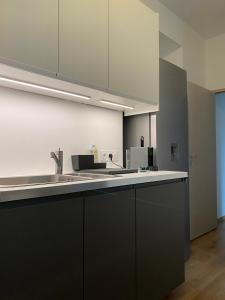 uma cozinha com armários pretos e um balcão branco em Villa des Thermes - T3 em Royat