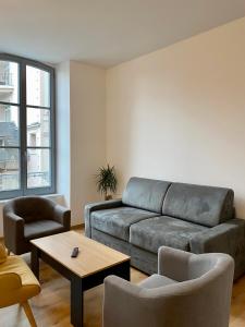 uma sala de estar com um sofá e uma mesa em Villa des Thermes - T3 em Royat