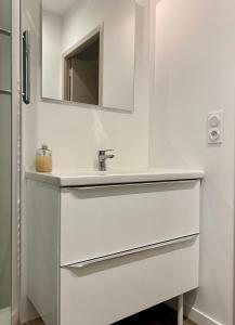 La salle de bains blanche est pourvue d'un lavabo et d'un miroir. dans l'établissement Villa des Thermes - T3, à Royat