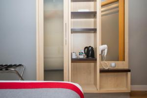 a bedroom with a cupboard with a phone and a bed at Holiday Inn Express Barcelona City 22@, an IHG Hotel in Barcelona