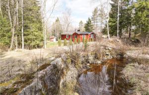 une maison rouge dans les bois à côté d'un ruisseau dans l'établissement Nice Home In Lilla Edet With House A Panoramic View, à Lilla Edet