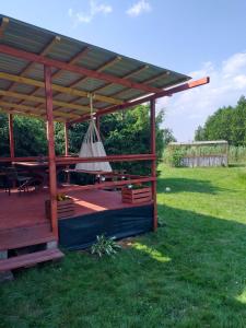 a wooden pergola with a picnic table in a field at Domek letniskowy na Mazurach nad stawem in Gromoty