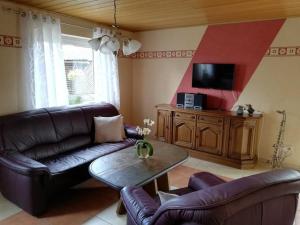 a living room with a leather couch and a table at Ferienwohnung Altmaier - Ferien auf dem Lande in Griebelschied