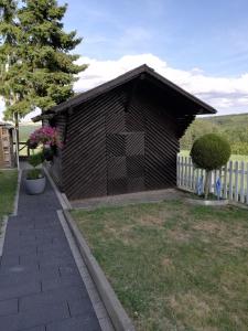 un pequeño edificio negro con una valla blanca en Ferienwohnung Altmaier - Ferien auf dem Lande, en Griebelschied