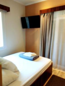 a bedroom with a bed with a television on the wall at ΕΚΑLI ROOMS APARTMENTS in Kalentzi