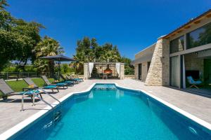 una piscina con sillas y una casa en Villa Potami Nikos by Villa Plus en Stílos