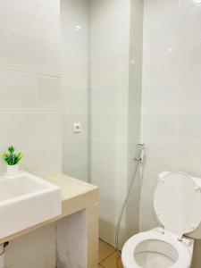 a white bathroom with a toilet and a sink at Hozby Skyview Setiabudi in Sunggal