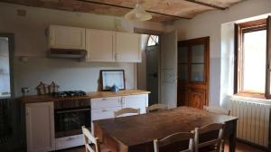 a kitchen with a wooden table and a dining room at Agriturismo Portoreschi in Saragano