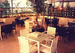 un comedor con mesas, sillas y un árbol en Torino Hotel Amman, en Amán