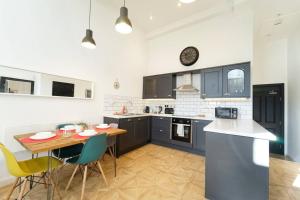 a kitchen with blue cabinets and a table and chairs at Spacious 2 bedroom city centre apartment in Leeds