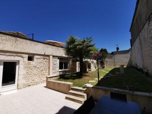 een binnenplaats met een gebouw en een palmboom bij L'Envie d'Eymet, gîte pour 6 personnes in Eymet