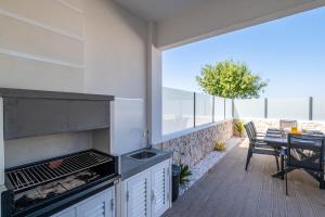 un patio con parrilla, mesa, mesa y sillas en Atlantis Luxury Villa by Atlantic Places, en Albufeira