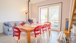 a dining room with a wooden table and red chairs at La Casa sulla Collina - Italian Homing in Padenghe sul Garda
