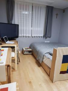 um quarto com uma cama, uma secretária e uma televisão em Gyeongbokgung Palace Seochon Christian Home - Foreigner Only em Seul