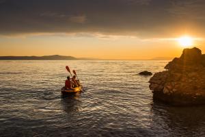 two people in a boat in the water at sunset at Apartment Petar - by the Sea in Gradac