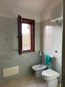 a bathroom with a toilet and a sink and a window at Villa Magnolia in Muravera