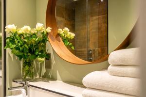 uma casa de banho com um espelho e um vaso de flores num lavatório em The Boutique York Garden Studio em York