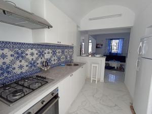 古萊比耶的住宿－Maison S+1 très bien équipée à 2mn de la plage，厨房配有白色橱柜和蓝色及白色瓷砖