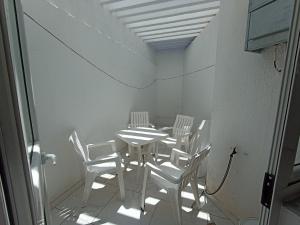 古萊比耶的住宿－Maison S+1 très bien équipée à 2mn de la plage，一间配备有白色椅子和桌子的用餐室