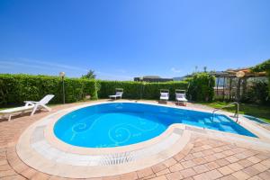 basen w ogrodzie z dwoma krzesłami wokół niego w obiekcie Villa Stefania w mieście Ischia