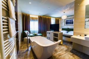 ein Badezimmer mit einer Badewanne und ein Schlafzimmer mit einem Bett in der Unterkunft Hotel Vienna beim Prater in Wien