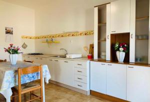 a kitchen with white cabinets and a table with flowers at Gallipoli Mancaversa Futura Vacanza Andrea in Marina di Mancaversa